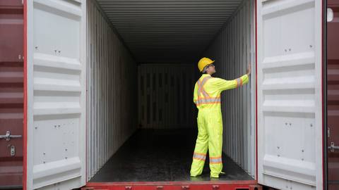 Inspector in hi-vis checking the interior of a shipping container
